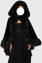 Load image into Gallery viewer, Model wearing a black faux fur-trimmed hooded cloak over a black dress on a white background