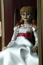 Load image into Gallery viewer, annabelle figure sitting in chair wearing white dress with hair in pig tails. sign reading "warning! positively do not open"