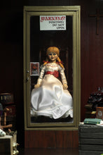 Load image into Gallery viewer, annabelle figure sitting in chair wearing white dress with hair in pig tails. sign reading "warning! positively do not open"