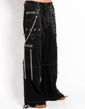 Load image into Gallery viewer, side view of Black baggy Tripp pants with white stitching. Pants have front rivet details, side pocket hanging chain details, removable attached chains, back zipper details and more. Pant legs can also zip off into shorts.