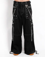 Load image into Gallery viewer, front view of Black baggy Tripp pants with white stitching. Pants have front rivet details, side pocket hanging chain details, removable attached chains, back zipper details and more. Pant legs can also zip off into shorts.