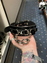 Load image into Gallery viewer, Black leather collar with silver D ring details, and two silver handcuffs hanging from two silver chains.