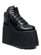 Load image into Gallery viewer, outer view of black vegan leather platform shoe with EVA platform. Shoe looks like a sneaker, but super tall! Shoe has nylon details and mesh lining. Bottom of platform has a "fanned" grip to make the platform more stable.