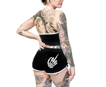 Load image into Gallery viewer, Women's black shorts with whitetrim and white skeleton hand middle finger design on right buttcheek, white drawstring and white cross bones on front left