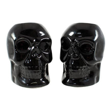 Load image into Gallery viewer, Black skull candlestick holders come in a set of two, and each holds a standard taper candle. CANDLES NOT INCLUDED.