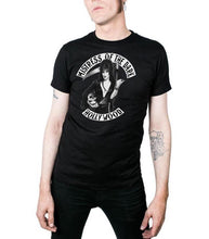 Load image into Gallery viewer, model wearing Black t-shirt with print of Elvira on front side. Print shows Elvira holding a skeleton and scythe. Top of shirt says "MISTRESS OF THE DARK" bottom says "HOLLYWOOD.