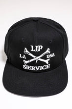 Load image into Gallery viewer, front view of Black hat with white embroidery that reads "LIP SERVICE LA USA" on the front with crossbones. Snaps on the back.