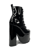 Load image into Gallery viewer, outer view of Black vegan shiny patent leather tall military style platform boot with black cotton laces and black inner zipper. Front of platform has a fanned grip for better stability when walking.