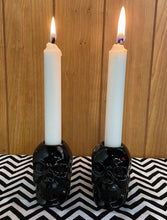 Load image into Gallery viewer, Black skull candlestick holders come in a set of two, and each holds a standard taper candle. CANDLES NOT INCLUDED.
