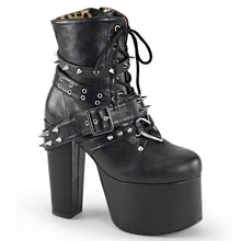Load image into Gallery viewer, outer side view of black vegan leather 5 1/2" heel 3" platform Lace-up front Ankle boot Features wrap around buckled straps with spikes & eyelets and heart O-ring on vamp with Inside zip closure