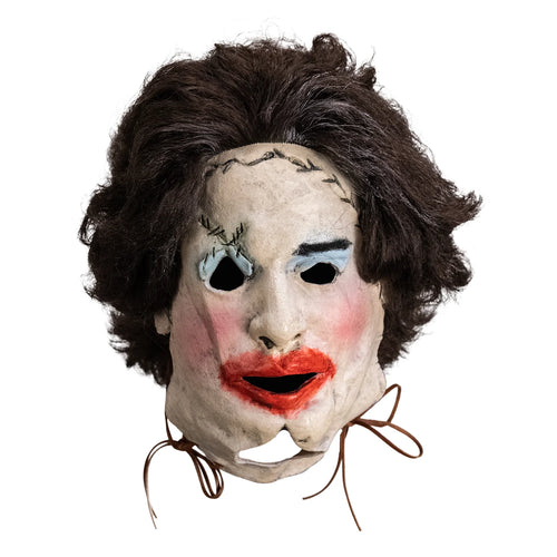 Mask with brown hair, white face, black eyes, red lips, and brown strings on a white background
