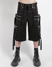 Load image into Gallery viewer, Waist-down view of baggy black punk-style cargo pants featuring silver pyramid studs, hanging side straps, a drawstring waist, and chunky black boots against a white background.
