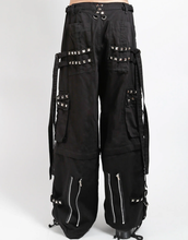 Load image into Gallery viewer, Waist-down view of baggy black punk-style cargo pants featuring silver pyramid studs, hanging side straps, a drawstring waist, and chunky black boots against a white background.
