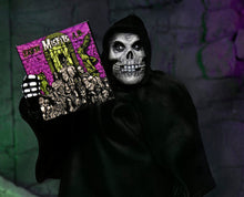 Load image into Gallery viewer, Figure in black hood holding a purple and green album cover with a dark, eerie background.
