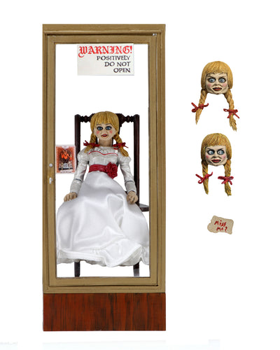 annabelle figure sitting in chair wearing white dress with hair in pig tails. interchangable heads on display. sign reading 