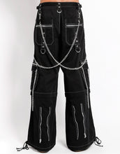 Load image into Gallery viewer, back view of Black baggy Tripp pants with white stitching. Pants have front rivet details, side pocket hanging chain details, removable attached chains, back zipper details and more. Pant legs can also zip off into shorts.
