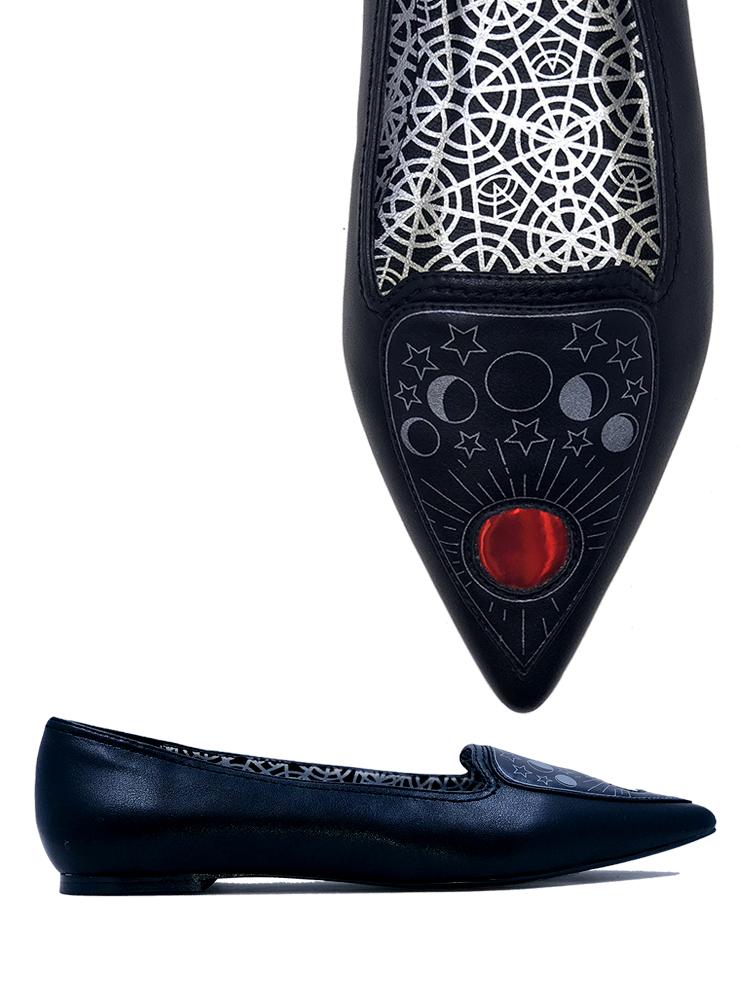 Black flats with pointy toe. Top of flats have silver Ouija board planchette print with red center. Inside sole of shoe is a black and white spiderweb-like pentagram print.