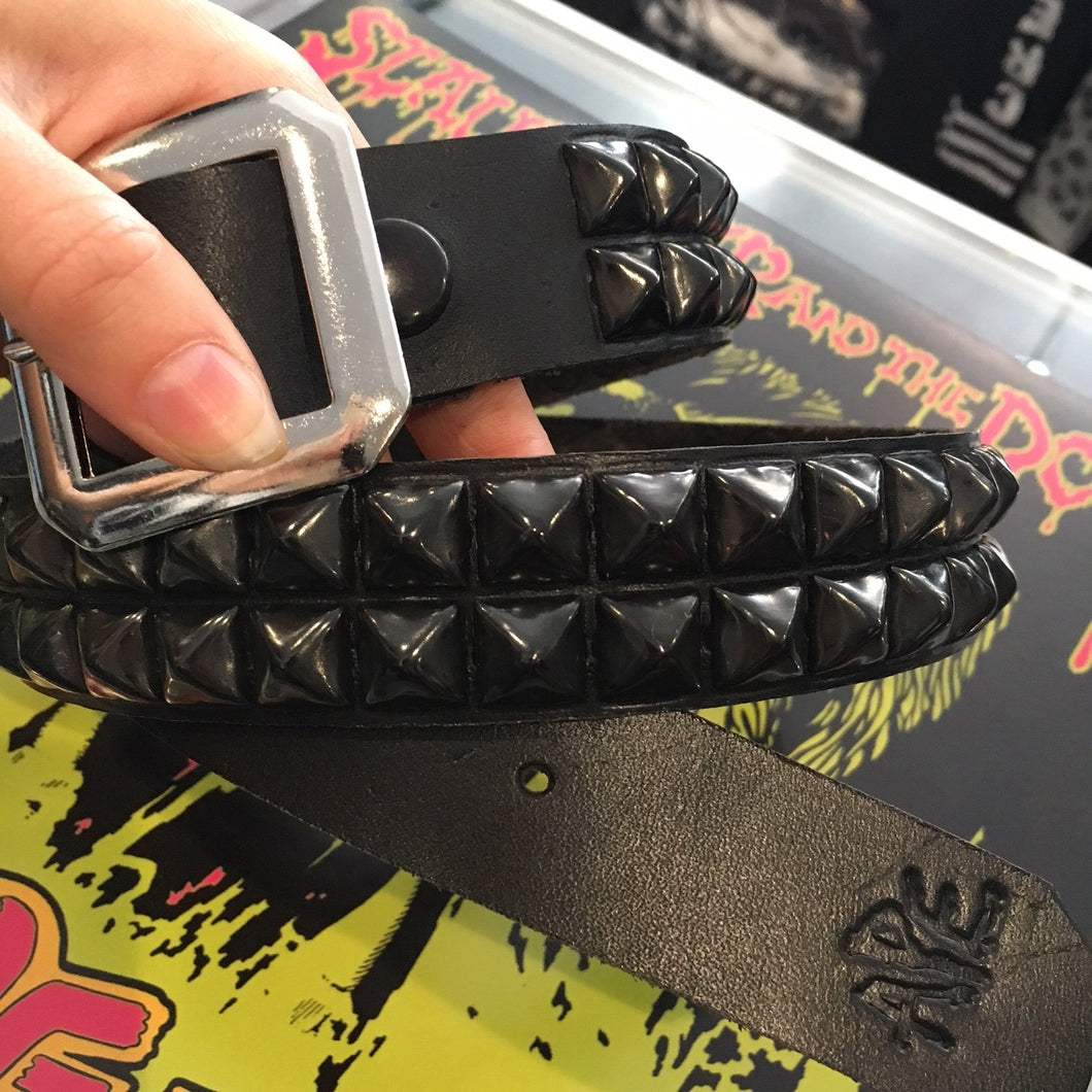 person holding black leather belt with two rows of black pyramid studs