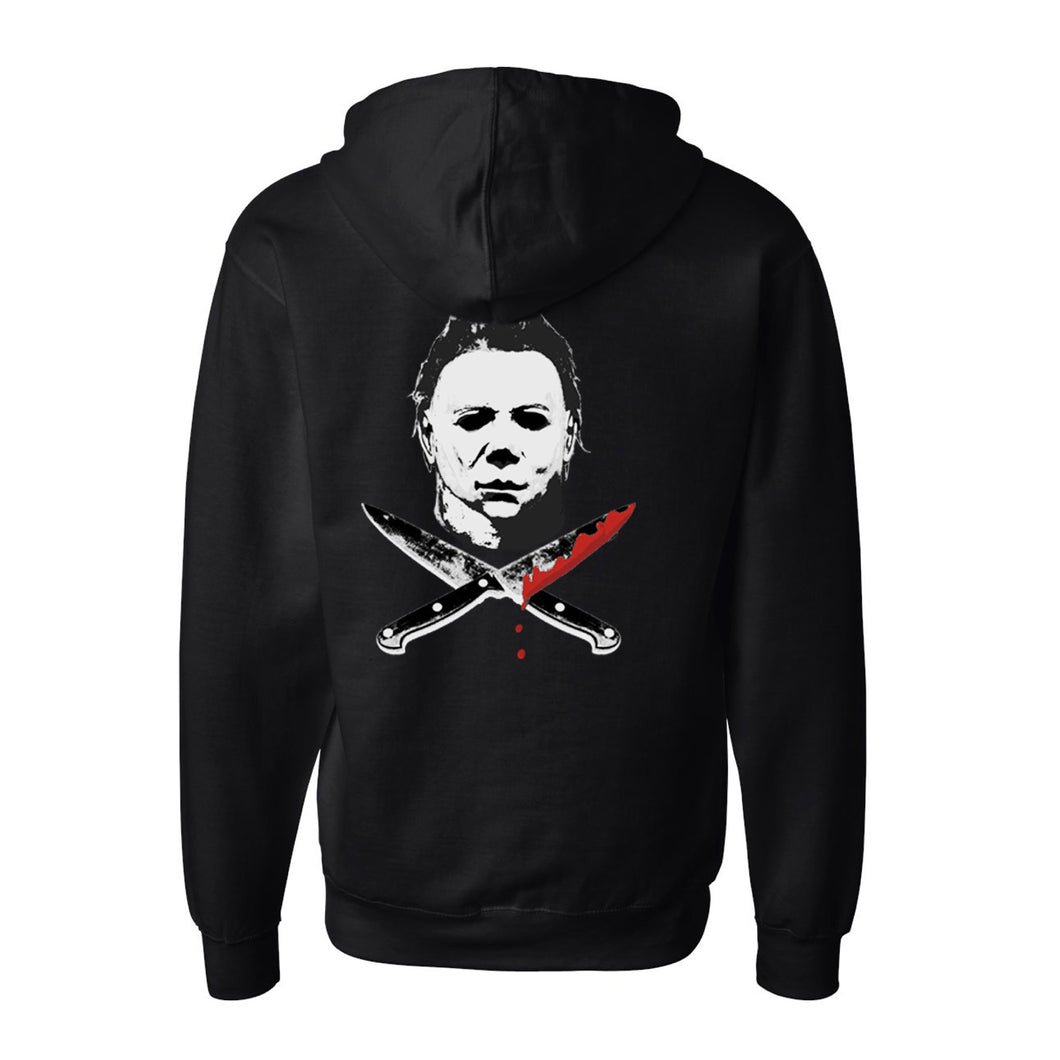 back of Black zip-up hoodie with Michael Myers mask on the back, with two knives crossed underneath. One knife has blood dripping from it. Front left side has a smaller version of the same image. 80% Cotton 20% Polyester.