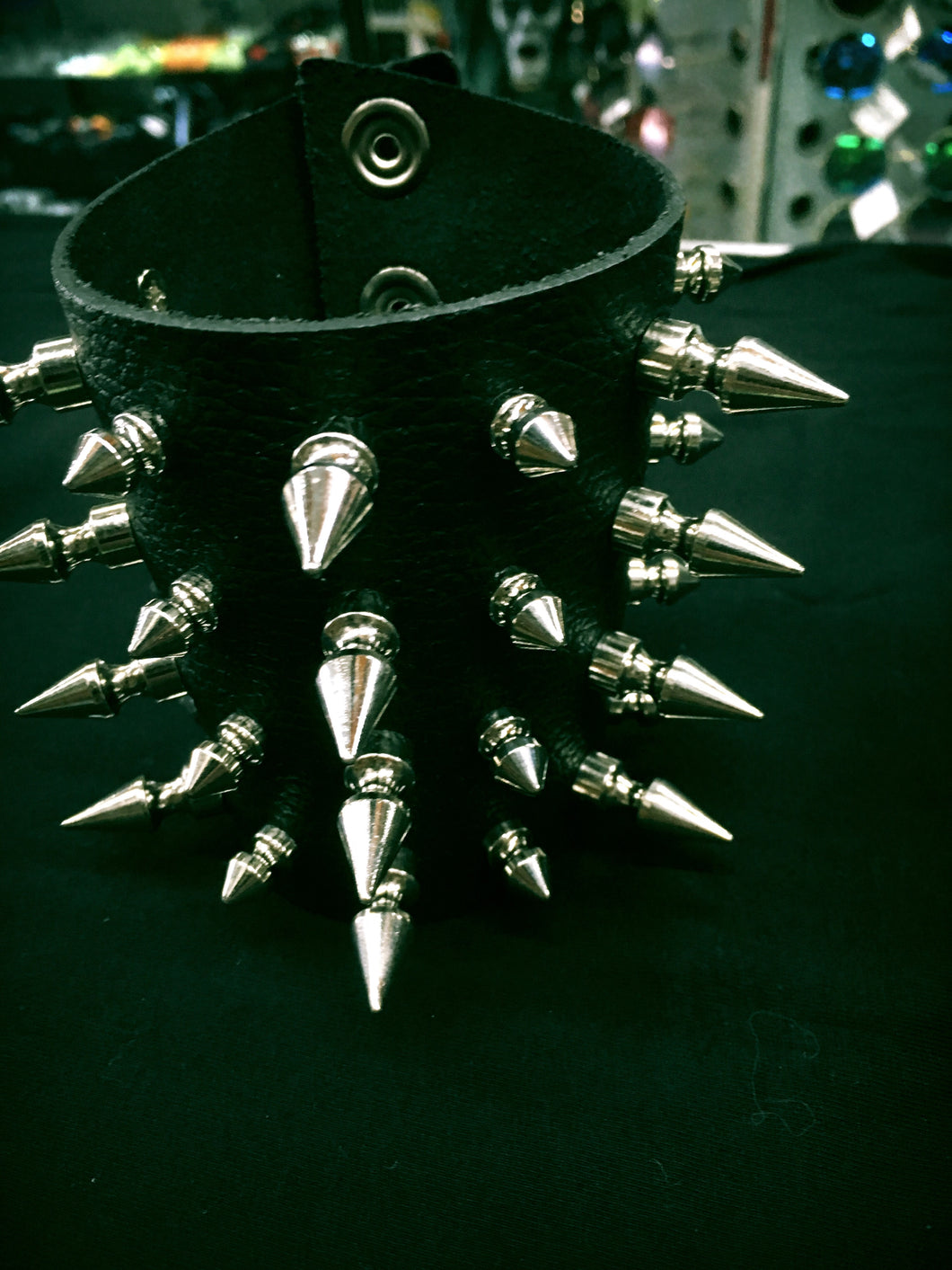 black leather gauntlet bracelet with four rows of different sized silver spikes. shows snap closure