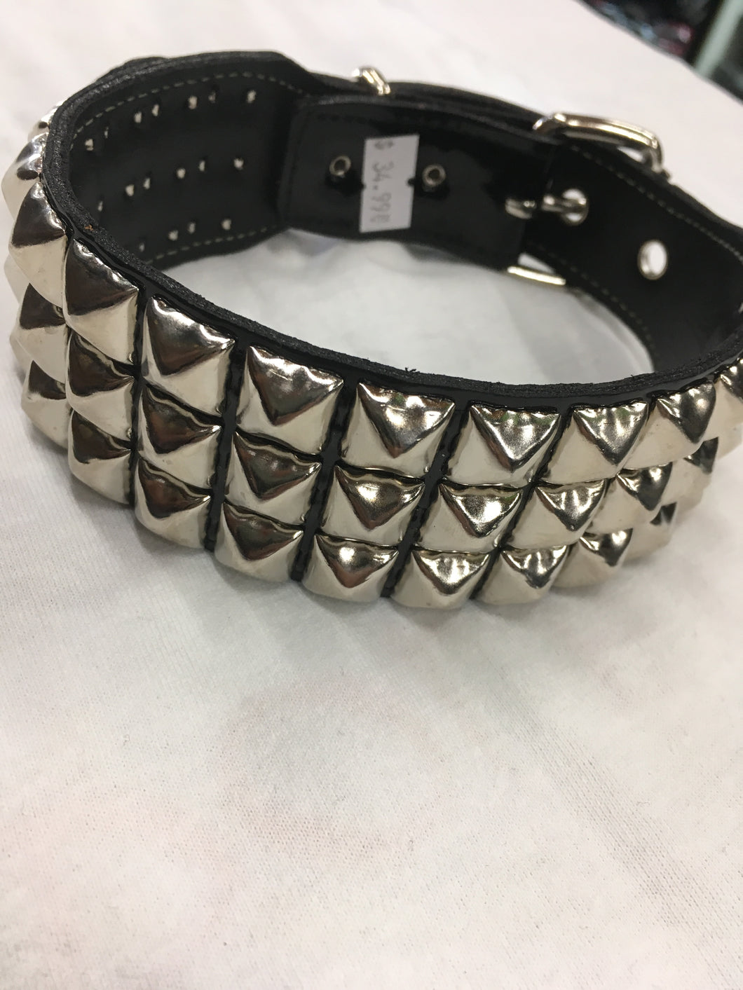 black leather collar with three rows of multiple silver pyramid studs. show adjustable buckle closure