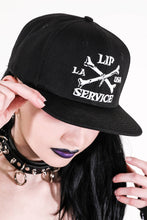 Load image into Gallery viewer, front view of Black hat with white embroidery that reads &quot;LIP SERVICE LA USA&quot; on the front with crossbones. Snaps on the back.
