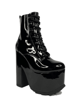 Load image into Gallery viewer, outer view of Black vegan shiny patent leather tall military style platform boot with black cotton laces and black inner zipper. Front of platform has a fanned grip for better stability when walking.
