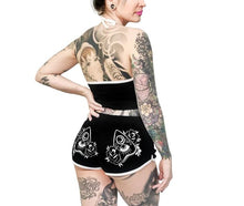 Load image into Gallery viewer, women&#39;s Black shorts with white trim and white planchette rose design on both buttcheeks, white drawstring and white spell book design on front left
